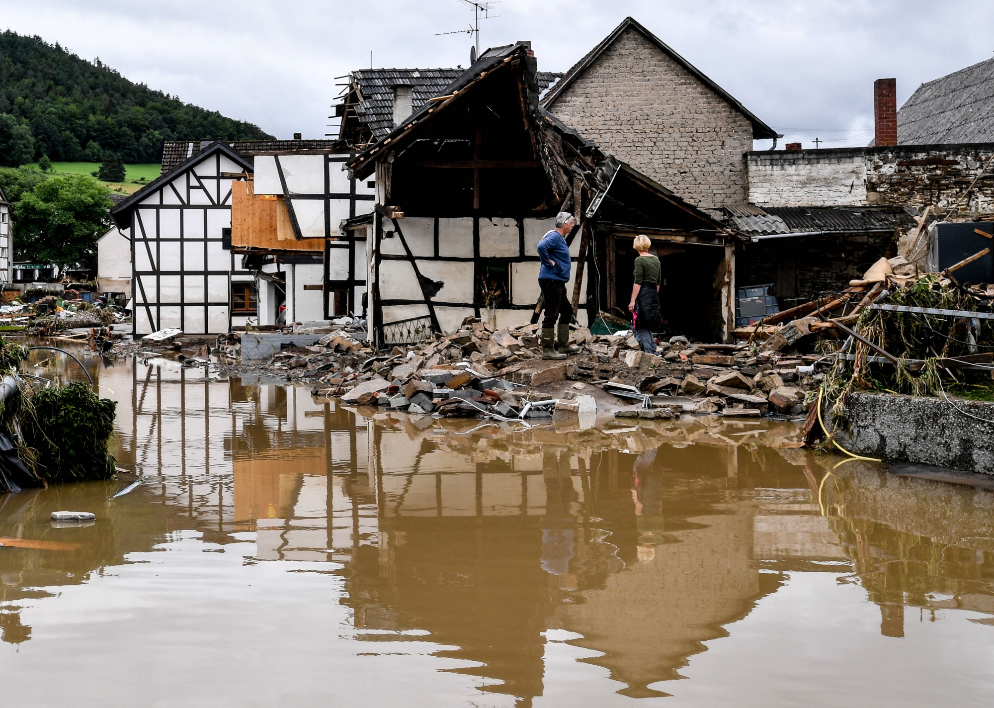 epa09345968 Local residents inspect a collapsed house after heavy flooding of the river Ahr, in Schuld, Germany, 15 July 2021. Large parts of Western Germany were hit by heavy, continuous rain in the night to 15 July, resulting in local flash floods that destroyed buildings and swept away cars EPA/SASCHA STEINBACH