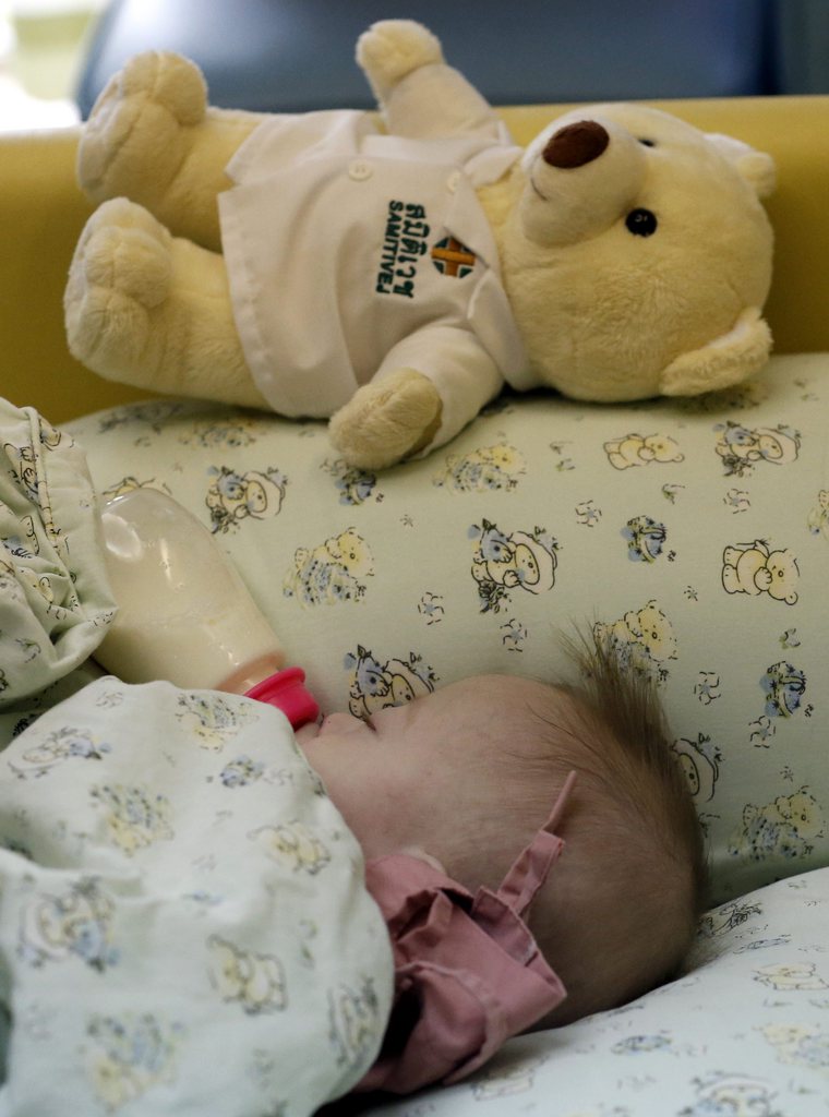 epa04340367 A Thai seven-month-old Down's Syndrome surrogate baby, Gammy or Naruebet Mincharoen drinks from a bottle of milk next to his Teddy bear at a hospital in Chonburi province, Thailand, 04 August 2014. The Australian father of a baby with Down's syndrome born to a surrogate in Thailand has denied abandoning the child while taking home his healthy twin sister. Gammy is one of twins born to Thai woman Pattharamon Janbua who said she was paid by the unidentified Australian couple to deliver an in vitro fertilized baby. The case sparked a public outcry and put a spotlight on transnational commercial surrogacy laws in Thailand and Australia.  EPA/RUNGROJ YONGRIT