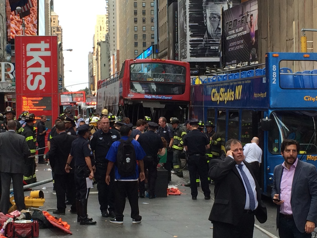 In this photo provided by tracedinc.com, people look as emergency personnel respond to a bus crash on Tuesday, Aug. 5, 2014, in New York City's Times Square. The accident occurred around 47th Street and Seventh Avenue in Manhattan. (AP Photo/tracedinc.com)