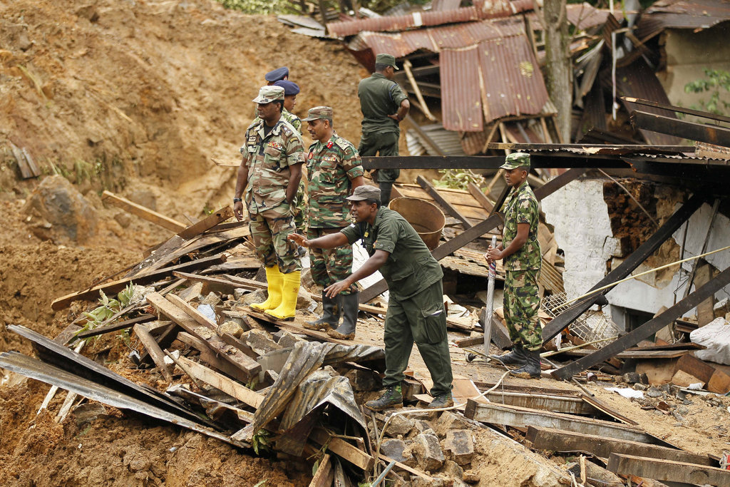 Sri Lankan army soldiers watch rescue operations at the site of a mudslide in at the Koslanda tea plantation in Badulla district, about 220 kilometers (140 miles) east of Colombo, Sri Lanka, Friday, Oct. 31, 2014. Disaster officials estimate that about 100 people were killed Wednesday morning when monsoon rains unleashed a cascade of muddy earth at the plantation and warned of more landslides at the area. (AP Photo/Eranga Jayawardena)