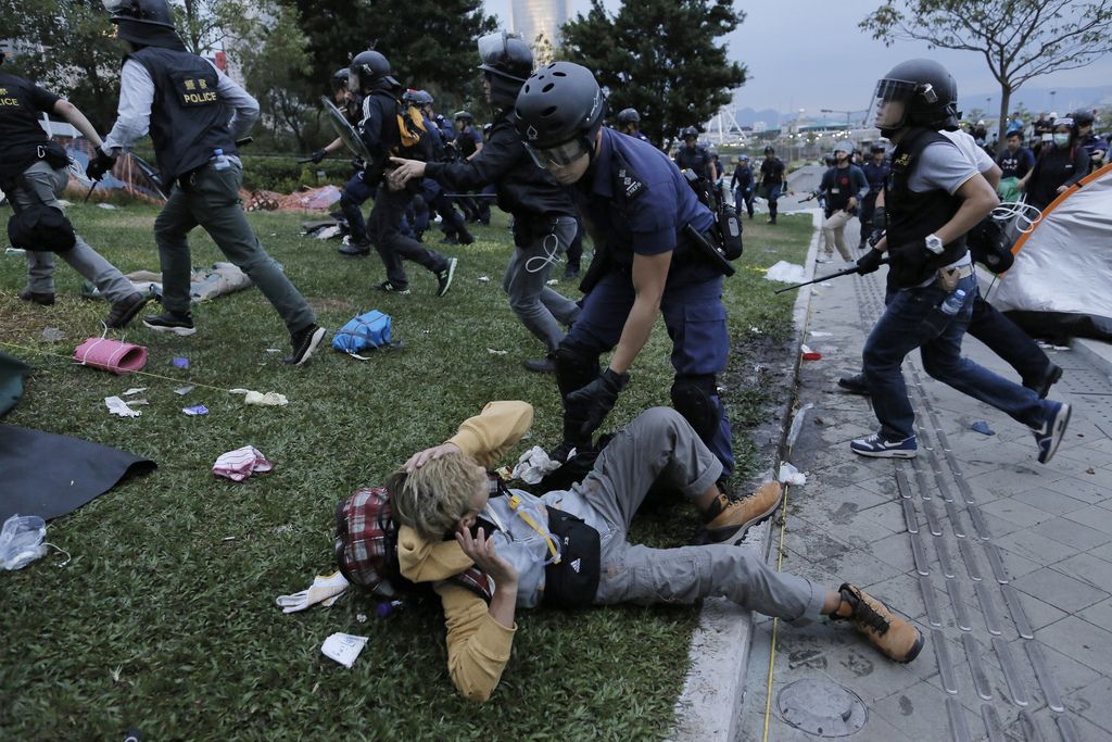 A protester falls down on the ground as he and others run away from police officers outside government headquarters in Hong Kong Monday, Dec. 1, 2014. Pro-democracy protesters clashed with police as they tried to surround Hong Kong government headquarters late Sunday, stepping up their movement for genuine democratic reforms after camping out on the city's streets for more than two months. (AP Photo/Vincent Yu)