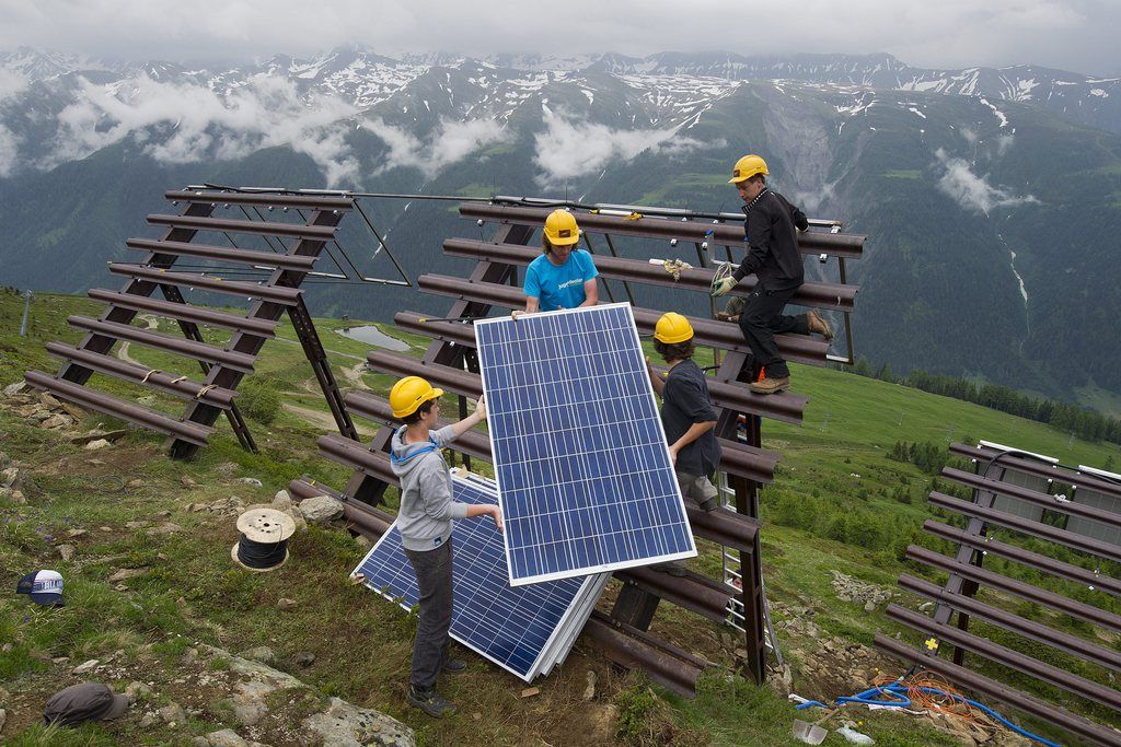 Des jeunes posent des panneaux solaires ou panneaux photovoltaiques sur des paravalanches.
