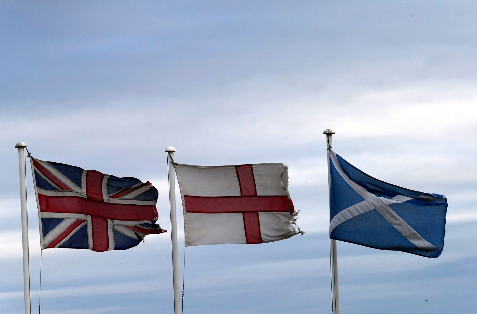From left, the Union Jack, St George's Cross and the Saltire fly at Adderstone, England, Monday, Sept. 8, 2014. The British government plans to offer Scotland more financial autonomy in the coming days as polls predict a very close vote in the September 18 on Scottish independence. (AP Photo/Scott Heppell) Britain Scottish Referendum