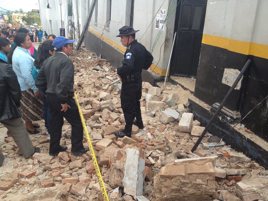 Dans les décombres, des gens questionnent un policier à San Marcos, au Guatemala. 