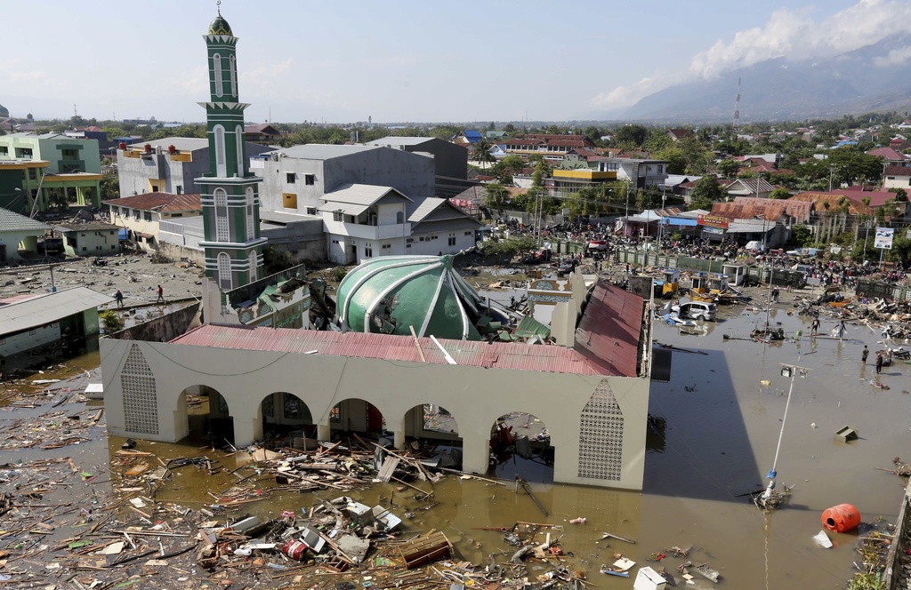 In this Sept. 30, 2018, photo, people survey the mosque damaged following earthquakes and tsunami in Palu, Central Sulawesi, Indonesia, Sunday, Sept. 30, 2018. A tsunami swept away buildings and killed hundreds on the Indonesian island of Sulawesi. A recent string of natural disasters, the latest a deadly earthquake and tsunami in Indonesia, have exacted a severe toll both in economic damage and human lives throughout Asia. The U.N. Office for Disaster Risk Reduction, or UNISDR, says up to 1.6 million people could be affected by the magnitude 7.5 earthquake and the tsunami that followed around dinnertime Friday in a remote area of Sulawesi island.(AP Photo/Tatan Syuflana, File)