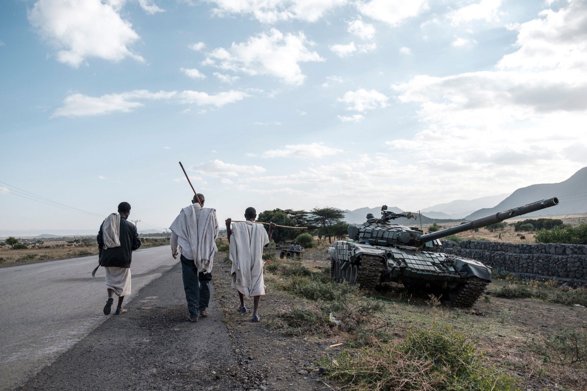 TOPSHOT - People walk next to an abandoned tank belonging to Tigrayan forces south of the town of Mehoni, Ethiopia, on December 11, 2020. The town of Mehoni, located in Southern Tigray, experienced shelling resulting in civilian deaths and injured people. (Photo by EDUARDO SOTERAS / AFP) (KEYSTONE/AFP/EDUARDO SOTERAS)