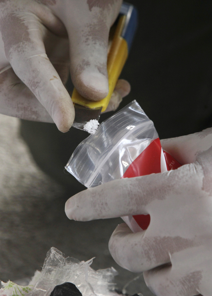 An anti-narcotic agent takes a sample of heroin during a press conference in Panama City, Monday, Aug. 1, 2011. According to police 639 packages of heroin and 468 packages of cocaine were seized in two different operations on Saturday and Sunday. (AP Photo/Arnulfo Franco)