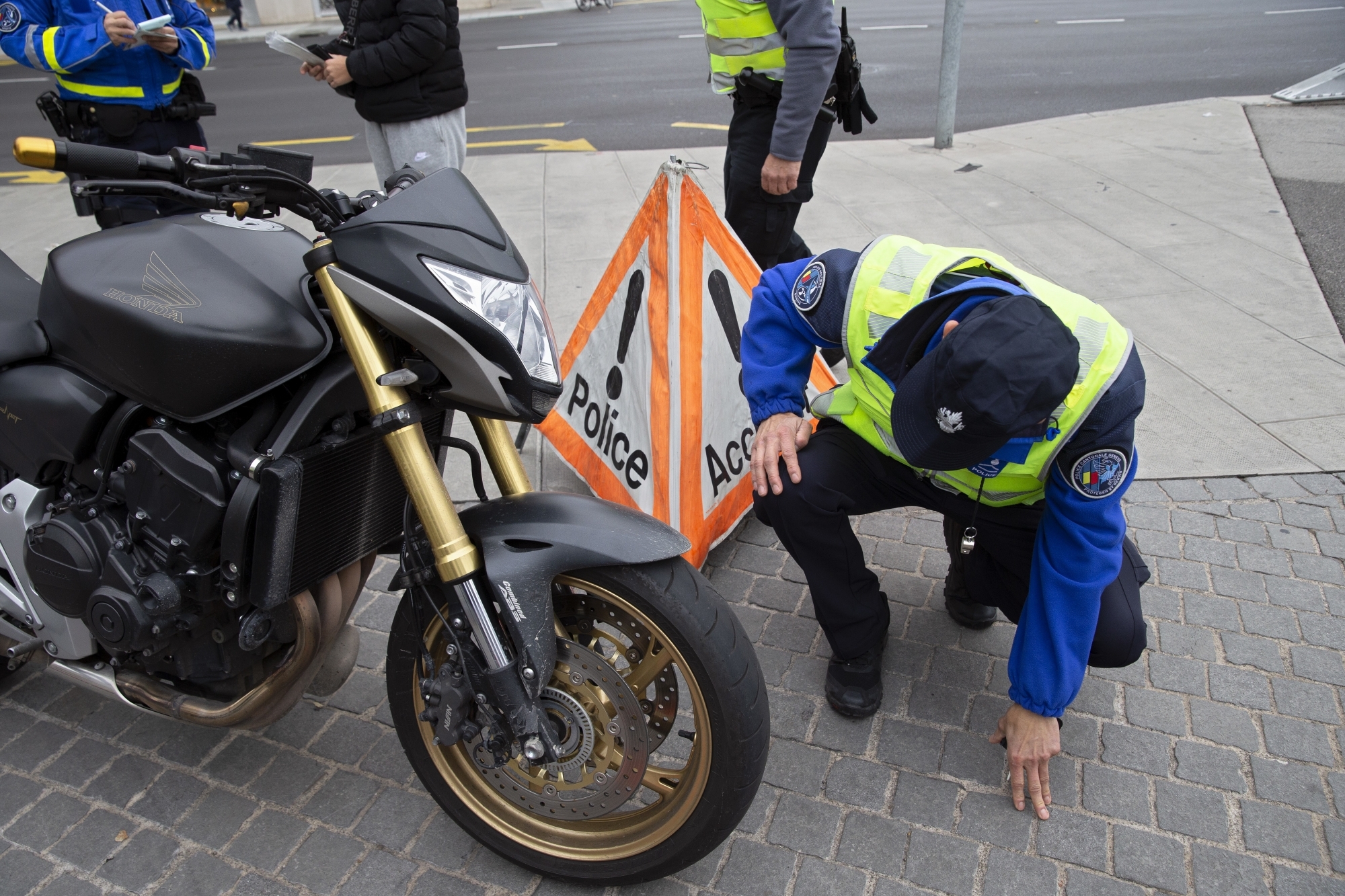 Un agent de la police genevoise contrôle le pneu d'une moto. 