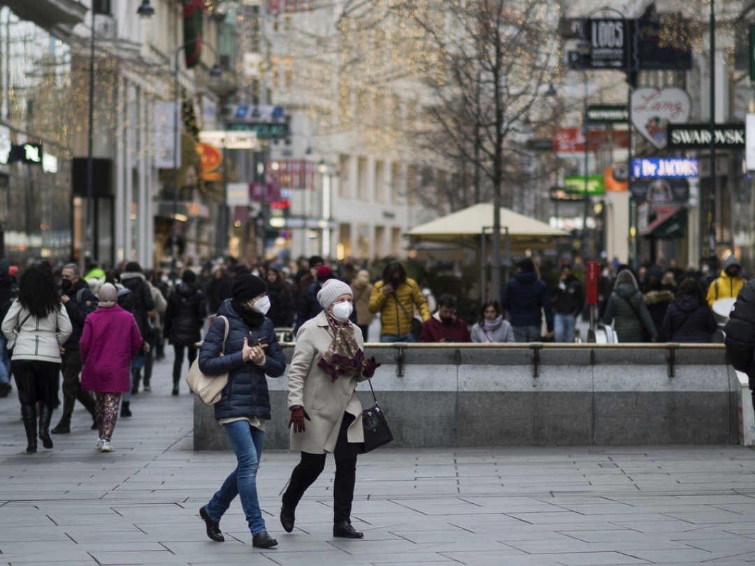 People wearing face mask to protect against the coronavirus as they walk at a shopping street in Vienna, Austria, Wednesday, Nov. 17, 2021. The Austrian a nationwide lockdown for unvaccinated people is in place to combat rising coronavirus infections and deaths. (AP Photo/Michael Gruber)