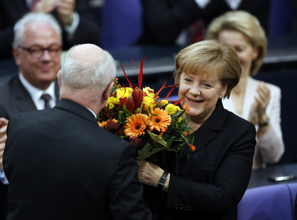 German Chancellor Angela Merkel receives flowers from well-wishers after being reelected during a meeting of the German federal parliament, Bundestag, in Berlin, Germany, Tuesday, Dec. 17, 2013. (AP Photo/Michael Sohn)