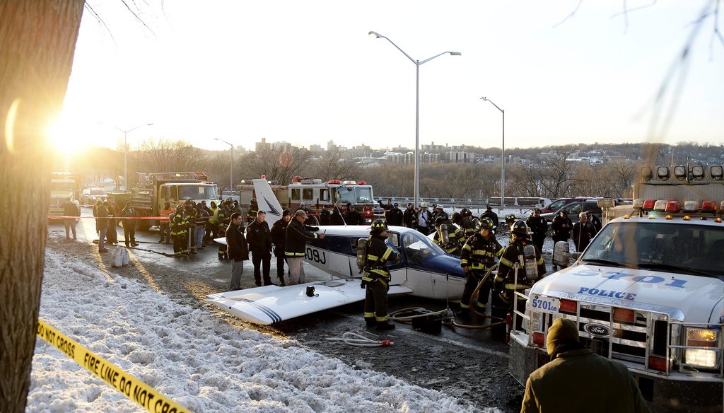 epa04008422 Rescue workers are seen around a small plane that landed on the Major Deegan Expressway in the Bronx, New York, USA, 04 January 2014. Three people were reportedly injured in the accident and there was no word on the cause of the emergency landing at this time.  EPA/ANDREW GOMBERT