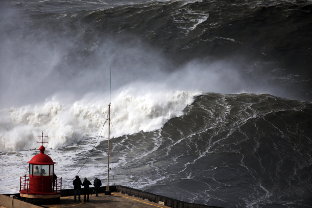 AP10thingsToSee - People watch huge waves approaching the lighthouse outside the fishing village of Nazare, in the central coast of Portugal on Sunday, Feb. 2, 2014. Many ports, most in in the north of the country, were closed due to the rough seas. (AP Photo/Francisco Seco, File)