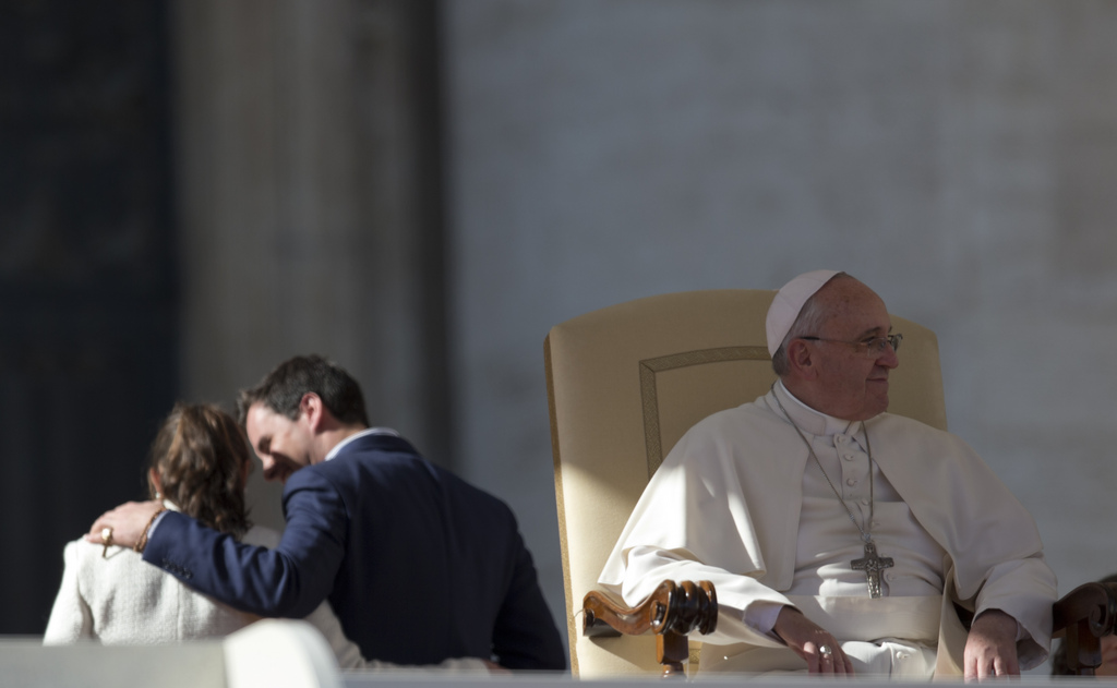 A couple passes behind pope Francis during a meeting with couples in St. Peter's Square at the Vatican, Friday, Feb. 14, 2014. Pope Francis met a group of engaged couples on Valentine's Day. (AP Photo/Alessandra Tarantino)