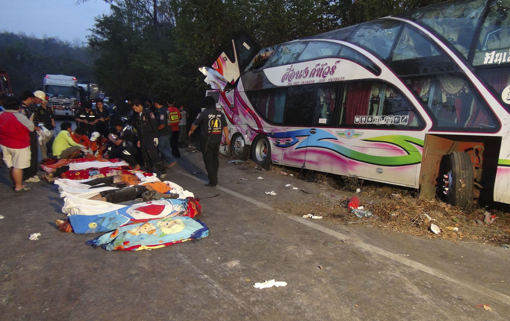 Emergency rescue workers recover bodies killed in a tour bus crash Friday morning, Feb. 28, 2014 in Prachinburi province, eastern Thailand. A double-decker tour bus carrying students on a school trip to the beach crashed Friday into a truck while traveling down hill, killing 15 people and injuring more than 30 others, police said. (AP Photo) THAILAND OUT