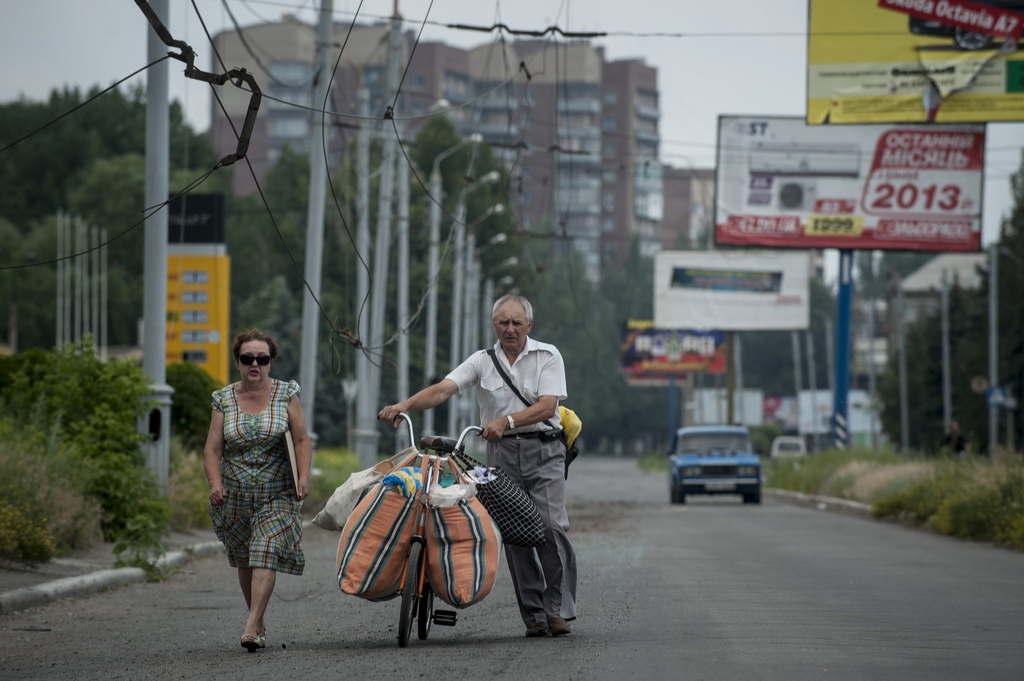 An Ukrainian family carry their belongings using a bicycle, as they leave Slovyansk, eastern Ukraine, Monday, June 9, 2014 after a mortar attack by Ukrainian government forces. Several buildings have been damaged by shelling in an eastern Ukraine city controlled by pro-Russian separatists, as the country?s president announced that negotiations are underway to bring the conflict to an end. (AP Photo/Evgeniy Maloletka)