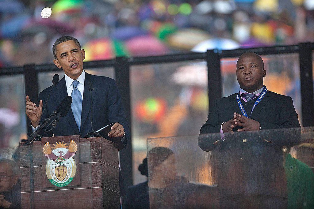 A photograph dated 10 December 2013 and made available 12 December 2013 showing US President Barrack Obama (L) speaking while the sign interpreter Thamsanqa Jantjie (R), stands during the US President's speech at the Nelson Mandela Memorial at FBN Stadium, Johannesburg, South Africa, 12 December 2013. The man accused of making up fake sign language, Thamsanqa Jantjie, gestures during the memorial service for Nelson Mandela this week attended by dozens of world leaders says he suffers from schizophrenia, according to interviews with media outlets on 12 December 2013.  EPA/STR SOUTH AFRICA OUT