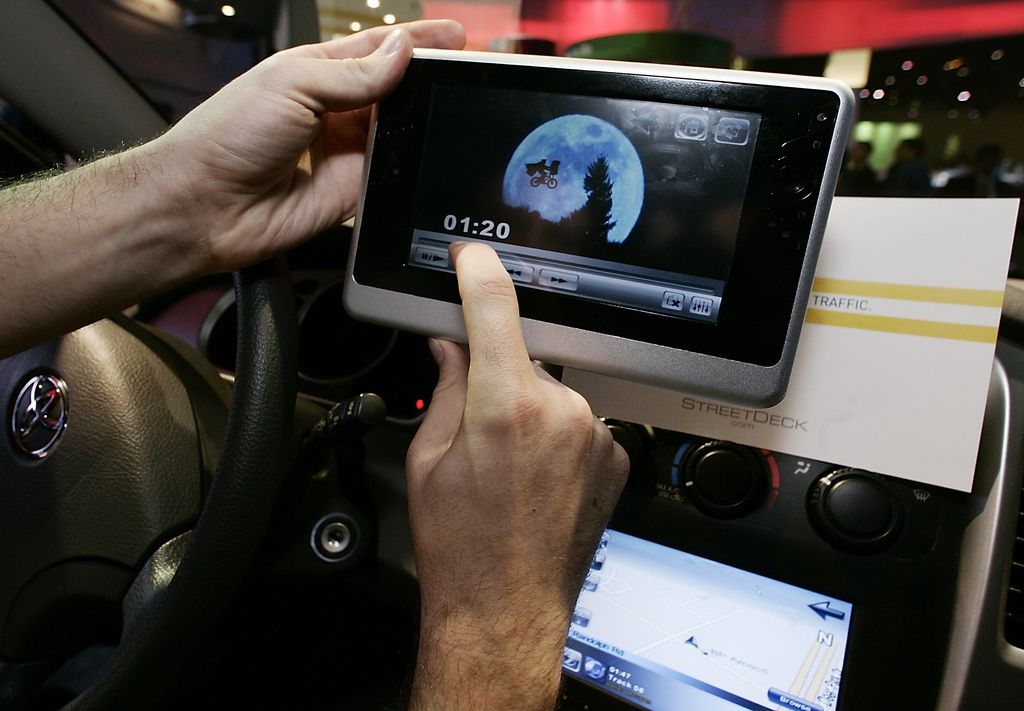 Robert Wray, Co-founder and CEO of StreetDeck.com from El Segundo, Calif., demonstrates a video played on an unreleased Intel-based computer tablet, next to his company's fully integrated Navigation and Entertainment System, below, for the digital car at the Consumer Electronics Show in Las Vegas, Saturday, Jan. 7, 2006. (KEYSTONE/AP Photo/Damian Dovarganes)