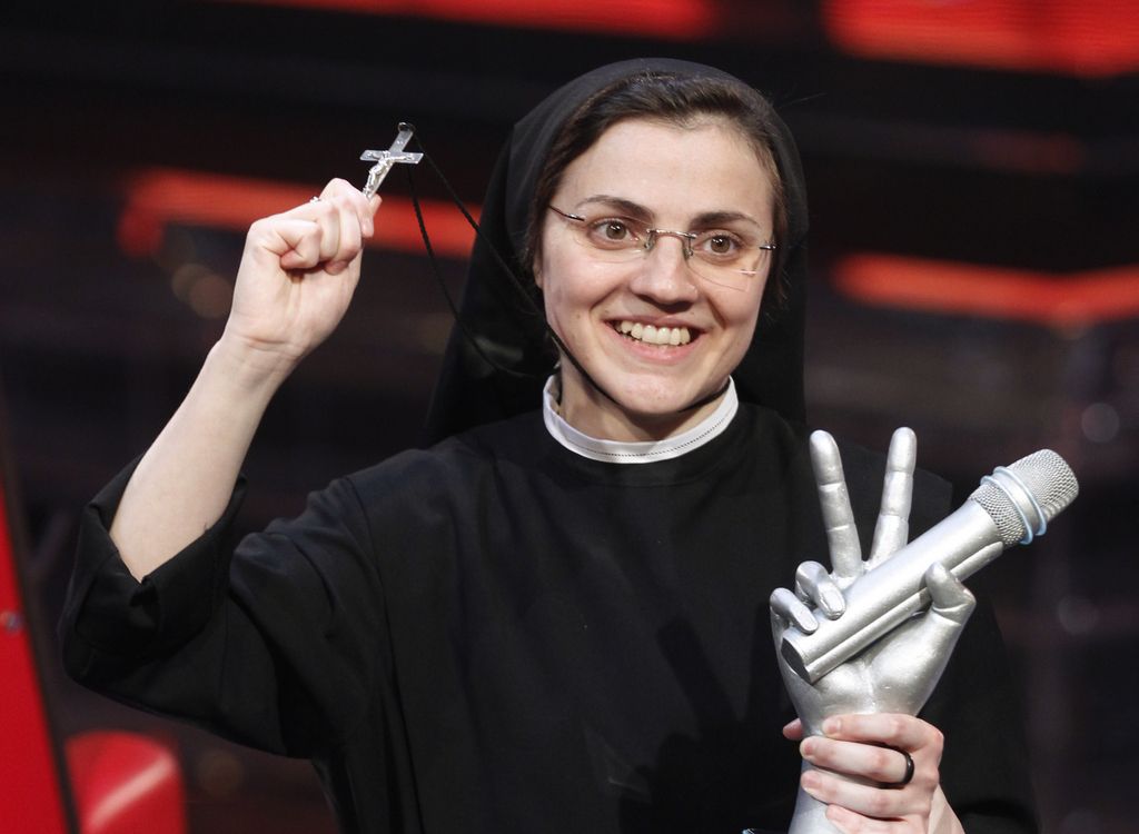 Sister Cristina Scuccia poses with the trophy and holding the cross on the stage after winning the final of the Italian version of the TV talent show "The Voice" in Milan, Italy, Thursday, June 5, 2014. With her full habit, sensible shoes and cheering nuns in her camp, Sister Cristina Scuccia made it to Thursday's finals of the Italian version of "The Voice" after capturing attention, and millions of YouTube viewers, with her first-round performance in March.  (AP Photo/Luca Bruno)