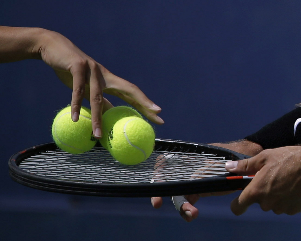 A ball runner places balls for service on the racket of Michal Przysiezny, of Poland, during a first round match against Julien Benneteau, of France, during the 2013 U.S. Open tennis tournament Tuesday, Aug. 27, 2013, in New York. (AP Photo/David Goldman)