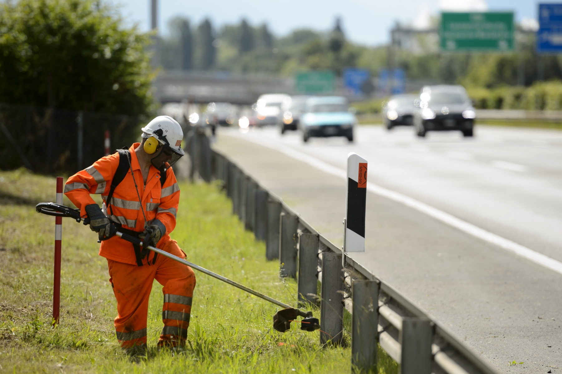 Un cantonnier vaudois, fauche à l'aide d'une débroussailleuse un talus le long de l'autoroute. 