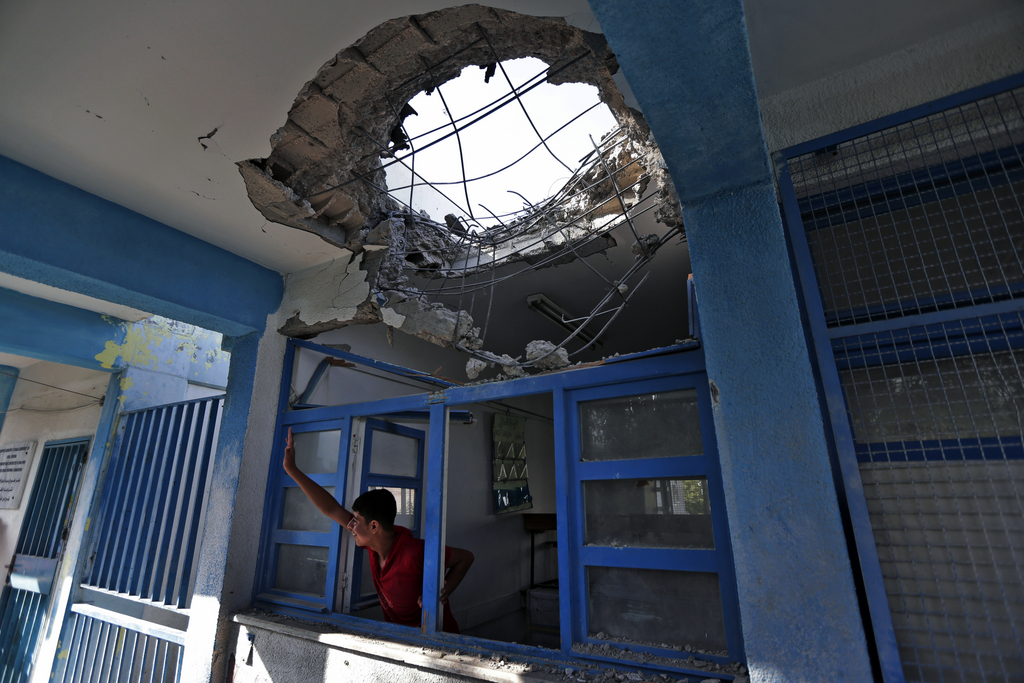 A displaced Palestinian child waves to a friend from inside a damaged classroom at the Abu Hussein U.N. school, in Jebaliya refugee camp, northern Gaza Strip, Wednesday, July 30, 2014.T he U.N. condemned Wednesday's attack on the school, with Secretary-General Ban Ki Moon calling it ?outrageous? and ?unjustifiable.? Israel said no U.N. facility had been intentionally targeted, but troops had responded to Hamas mortar fire nearby.  (AP Photo/Lefteris Pitarakis)