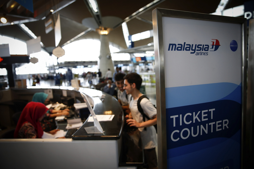 Passengers stand in front of information desk at Kuala Lumpur International Airport in Sepang, Malaysia, Friday, Aug. 8, 2014. Malaysia's state investment company said Friday it plans to make Malaysia Airlines fully government owned, removing it from the country's stock exchange before carrying out a far-reaching overhaul of the carrier that is reeling from double disasters. (AP Photo/Vincent Thian)