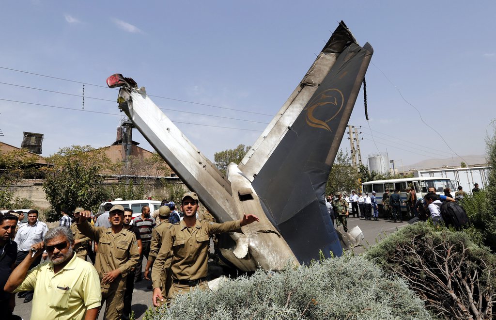 epa04347962 Iranian soldiers gesture as they stand near the tail of a crashed airplane in Tehran, Iran, 10 August 2014. At least 40 passengers on an Iranian passenger jet were reported dead after it crashed shortly after take-off near Tehran's airport, the Irna news agency reported, citing the Iran Red Crescent Society. The plane was departing Tehran's Mehrabad airport on its way to Tabas, in the country's east.  EPA/ABEDIN TAHERKENAREH