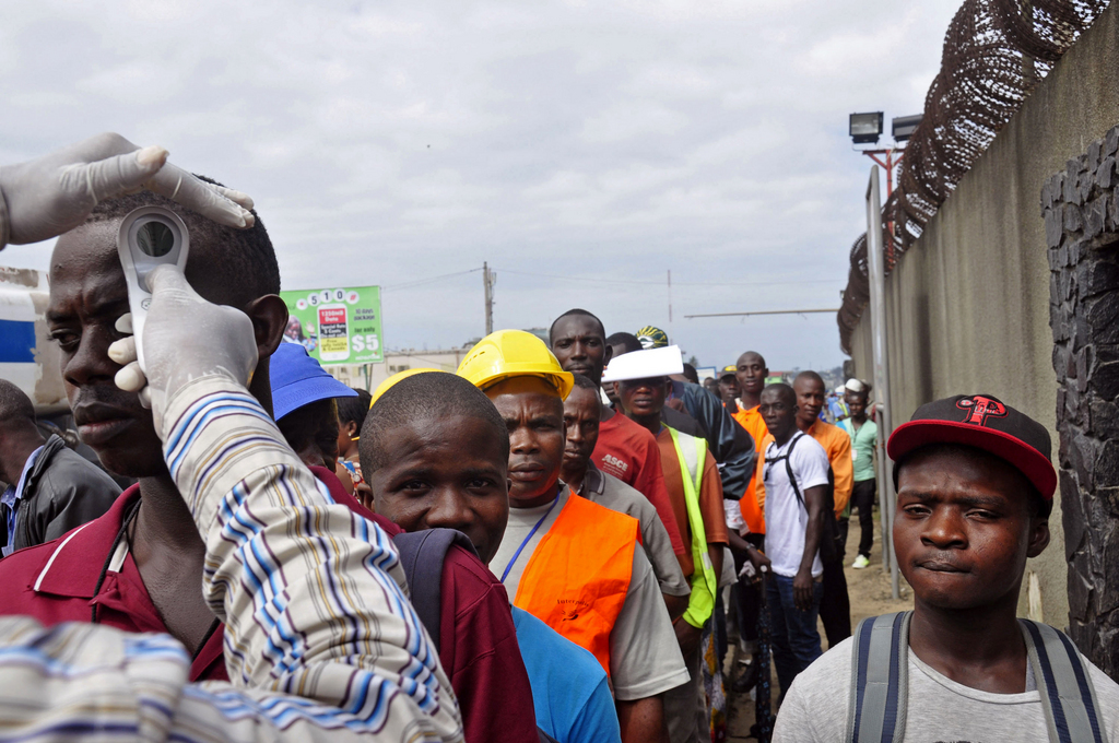 Workers have their temperature taken before entering the Freeport area, an important commercial port facility, Monrovia, Liberia, Monday, Aug. 11, 2014. Experts say fear and misunderstanding of Ebola have led many to ignore medical advice, fueling the disease's spread. (AP Photo/Abbas Dulleh)