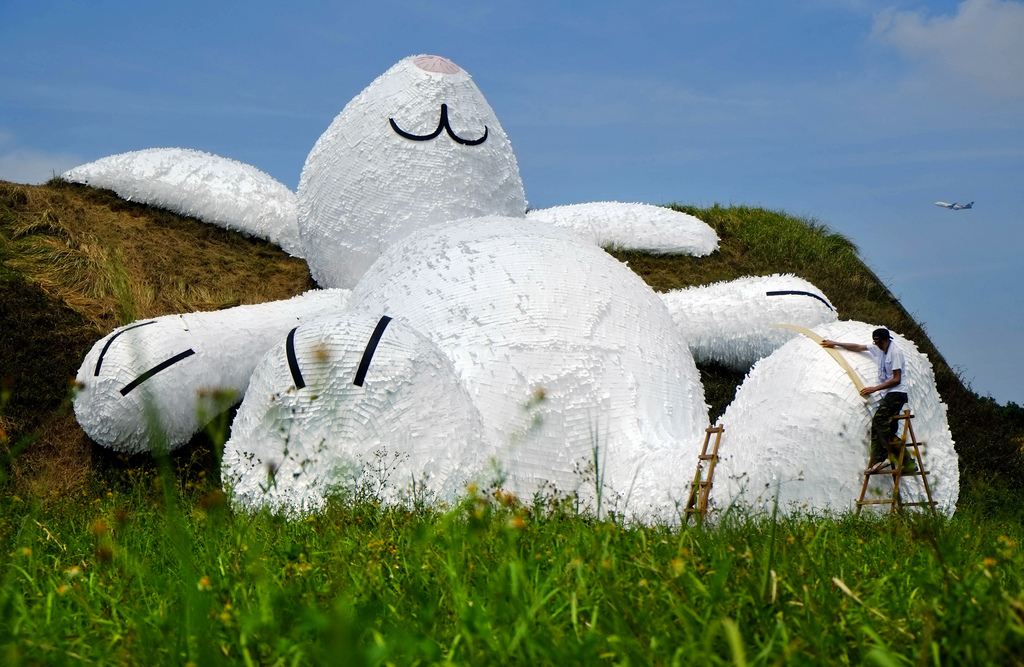 Dutch artist Florentijn Hofman's latest creation, a 25 meters (82 feets) white rabbit, leans up against an old aircraft hangar as part of the Taoyuan Land Art Festival in Taoyuan, Taiwan, Tuesday, Sept. 2, 2014. Hofman's big yellow duck drew millions of visitors as it toured the island last year and festival organizers are hoping the rabbit will do the same. The Taoyuan Land Art Festival will take place from Sept. 9-14. (AP Photo/Wally Santana)