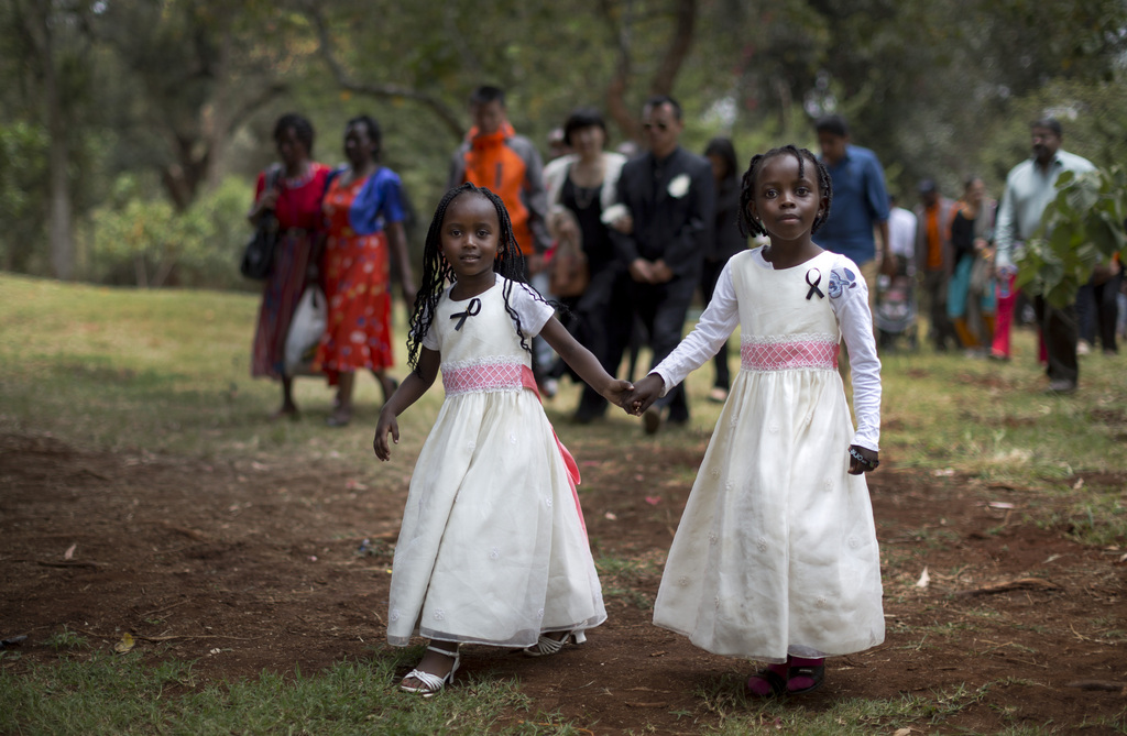 Gloria, 4, left, whose father Christopher Chewa was killed in the Westgate Mall attack, walks with her cousin Miriam, 6, right, and other families of the victims to lay flowers and remember at the Amani Garden memorial site in the Karura Forest in Nairobi, Kenya Sunday, Sept. 21, 2014. Kenya is marking one year since four gunmen stormed the upscale Westgate Mall in Nairobi, killing 67 people, and a memorial plaque with the names of the victims was unveiled at the popular forest on the edge of the city. (AP Photo/Ben Curtis)