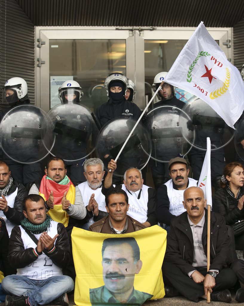 epa04435700 Kurdish protesters hold flags as riot police guard the main entrance of the European Parliament during a demonstration calling for support for the Syrian Kurdish town of Ain al-Arab, known as Kobane, currently besieged by the Islamic State (IS), in Brussels, Belgium, 07 October 2014. Islamic State jihadists pushed into the key Syrian town of Ain al-Arab (Kobane) on the Turkish border, seizing three districts in the city's east after fierce street fighting with its Kurdish defenders.  EPA/OLIVIER HOSLET