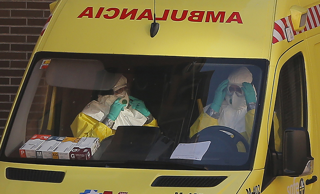 An ambulance with medical staff wearing rompers and gloves arrives at the apartment of a Spanish nurse infected with Ebola in Madrid, Spain, Wednesday, Oct. 8, 2014. Three more people were placed under quarantine for Ebola at a Madrid hospital where the Spanish nurse became infected, authorities said Thursday. More than 50 other possible contacts were being monitored. The nurse, who had cared for a Spanish priest who died of Ebola, was the first case of Ebola being transmitted outside of West Africa, where a months-long outbreak has killed at least 3,500 people and infected at least twice as many. (AP Photo/Andres Kudacki)