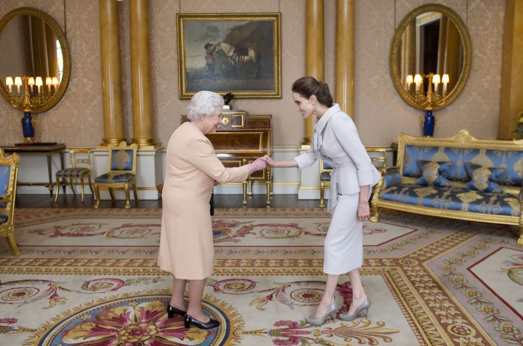 U.S actress Angelina Jolie, right, is presented with the Insignia of an Honorary Dame Grand Cross of the Most Distinguished Order of St Michael and St George by Britain's Queen Elizabeth II at Buckingham Palace, London, Friday, Oct. 10, 2014. Jolie received an honorary damehood (DCMG) for services to UK foreign policy and the campaign to end war zone sexual violence. (AP Photo/Anthony Devlin, PA Wire)     UNITED KINGDOM OUT    -   NO SALES    -   NO ARCHIVES