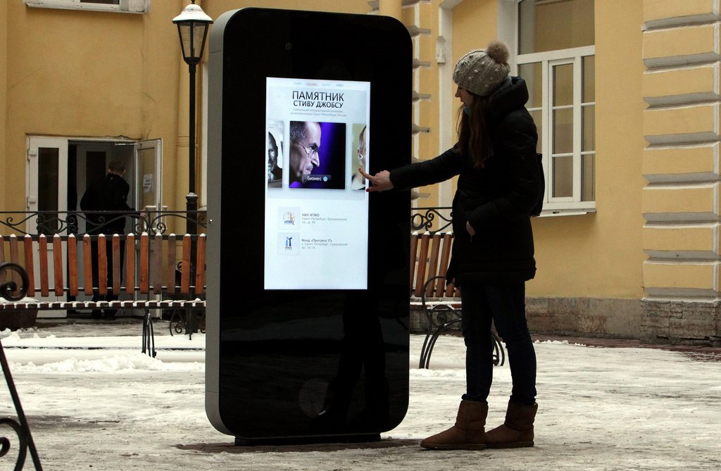 epa03529864 A girl touches the screen showing a portrait of Steve Jobs on the first Russian memorial to late Apple Corp. co-founder in the courtyard of the Techno Park of the St Petersburg National Research University of Information Technologies, Mechanics and Optics (ITMO University) in St Petersburg, Russia, 10 January 2013. The six-foot tall interactive memorial in the shape of a giant iPhone was unveiled on 09 January 2013.  EPA/ANATOLY MALTSEV