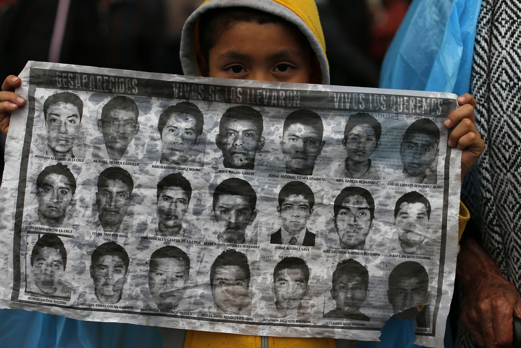 A young boy holds up a sheet with photos of some of the missing 43 students as protesters begin to gather at the Independence monument in Mexico City,Thursday, Nov. 20, 2014. Protesters marched to demand authorities find 43 missing college students, trying to step up pressure on the government on a day traditionally reserved for the celebration of the 1910-17 Revolution. (AP Photo/Dario Lopez-Mills)