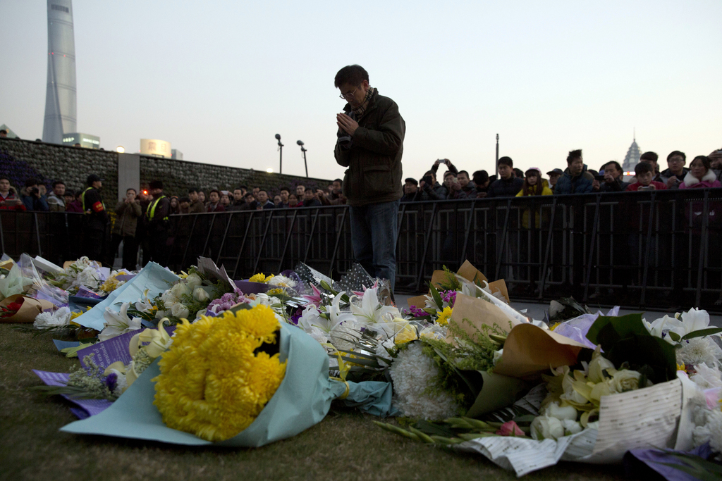 A man prays after laying flowers at the site of a deadly stampede in Shanghai, China, Thursday, Jan. 1, 2015. People unable to contact friends and relatives streamed into hospitals Thursday, anxious for information after a stampede during New Year's celebrations in Shanghai's historic waterfront area killed dozens of people in the worst disaster to hit one of China's showcase cities in recent years. (AP Photo/Ng Han Guan)
