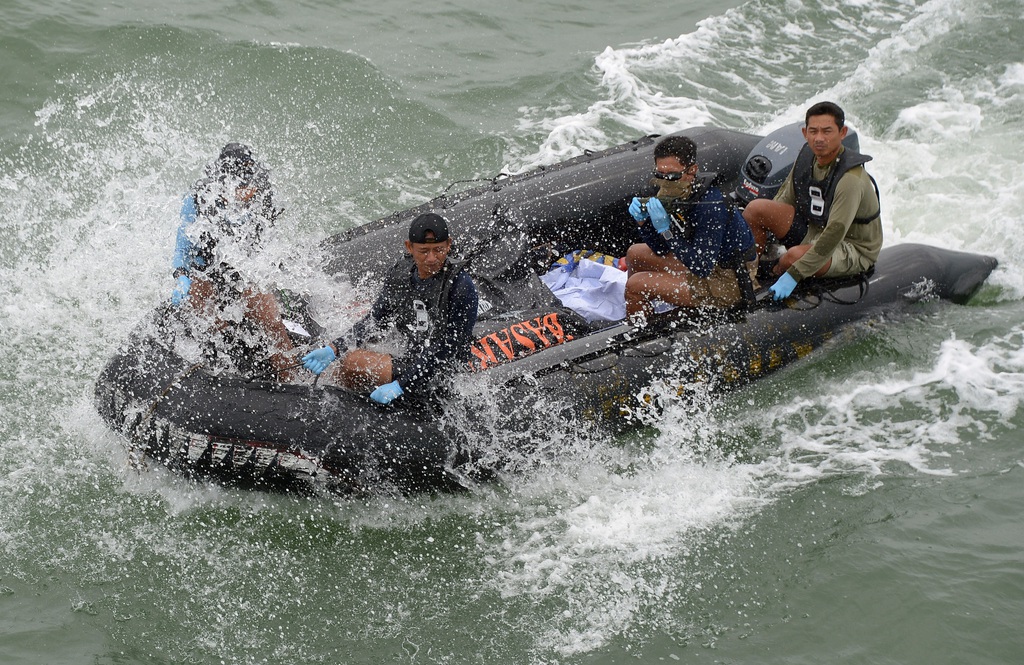 Indonesian Navy personnel carry a plastic bag containing the dead body of a passenger of AirAsia Flight 8501 at sea off the coast of Pangkalan Bun, Indonesia, Saturday, Jan. 3, 2015. Indonesian officials were hopeful Saturday they were honing in on the wreckage of the flight after sonar equipment detected two large objects on the ocean floor, a full week after the plane went down in stormy weather. (AP Photo/Adek Berry, Pool)