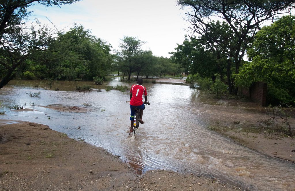 Un homme roule en bicyclette à travers les pluies diluviennes que subit le Malawi.
