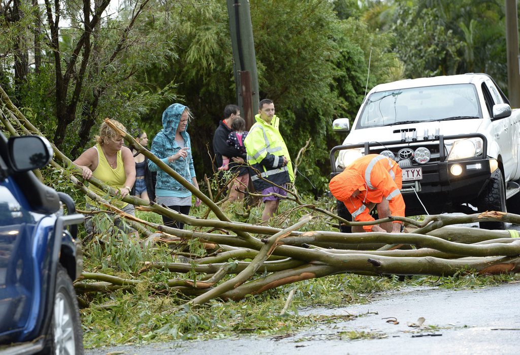 epa04628414 People remove a fallen tree from the road in the aftermath of Tropical Cyclone Marcia that hit Yeppoon, Queensland, Australia, 20 February 2015. The small town on the Capricorn Coast is bearing the brunt of the wild weather. According to media reports, Cyclone Marcia has been downgraded from Category Five to Category Four. The cyclone is still expected to be very destructive with wind gusts close to 300 kph.  EPA/KARIN CALVERT AUSTRALIA AND NEW ZEALAND OUT