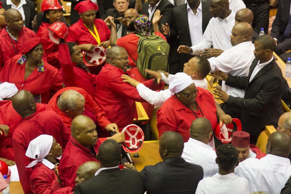 epa04616510 Members of the Economic Freedom Fighters (EFF), in red, clash with members of South African security forces after being ordered out of the National Assembly by the speaker of parliament during the State Of the Nation Address in Cape Town, South Africa, 12 February 2015. The State of the Nation address was disrupted by the EFF resulting in the party being ordered out of the chamber by security forces.  EPA/RODGER BOSCH/POOL