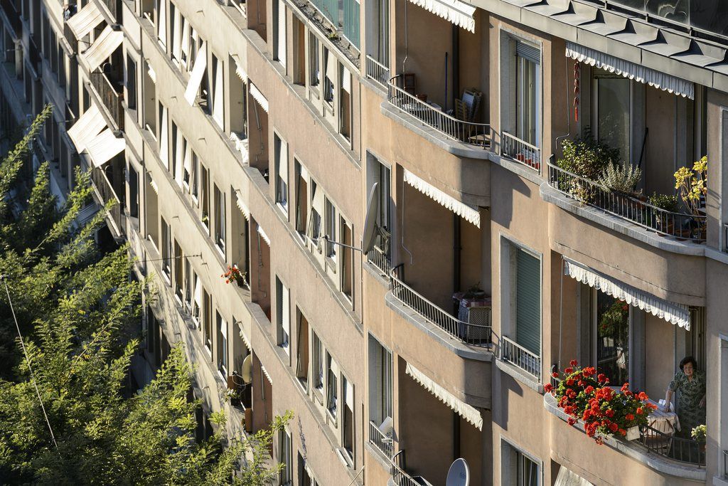 Une femme arrange ses geraniums sur son balcon d'un immeuble a la rue St.-Martin lors d'une manifestation " Un toit est un droit ! " contre les loyers exorbitants et la speculation immobiliere et pour le droit au logement ce jeudi 11 octobre 2012 a Lausanne. (KEYSTONE/Laurent Gillieron)