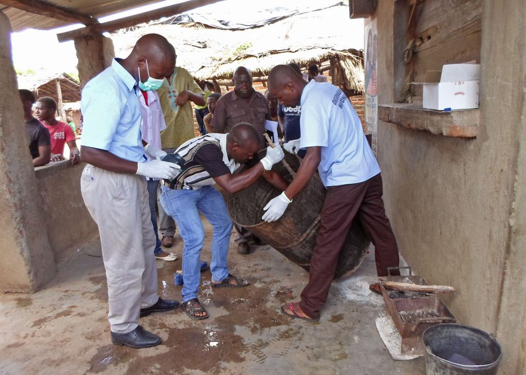 Mozambique government officials gather samples from a drum that was used to brew traditional local beer that killed 69 people in Tete, Mozambique, Monday, Jan 12, 2015.  69 people have died after drinking the beer, which is believed to have been laced with poisonous bile collected from a dead crocodile.  The deadly greenish-brown liquid, produced in the liver and stored in the gallbladder of a dead crocodile, is now believed to have been put into the traditional beer that killed 69 people who drank it at a funeral on Saturday in Mozambique's northeast Tete province, health authorities said.(AP Photo/Antonio Chimundo)