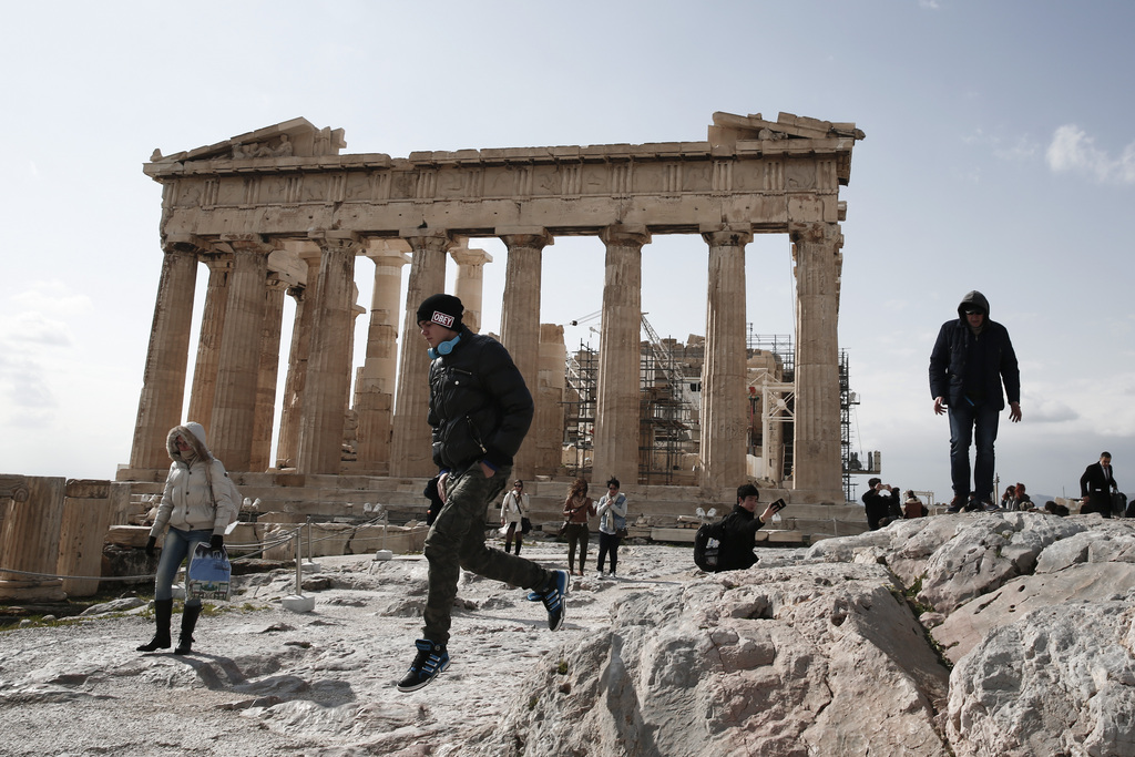 A tourist jumps in front of the ancient Parthenon temple at the Acropolis hill, in Athens, on Tuesday, Feb. 17, 2015. Greek shares led a European retreat Tuesday as investors reacted negatively to the breakdown in talks between Greece and its creditors in the 19-nation eurozone over the country's attempt to renegotiate its financial bailout. (AP Photo/Petros Giannakouris)