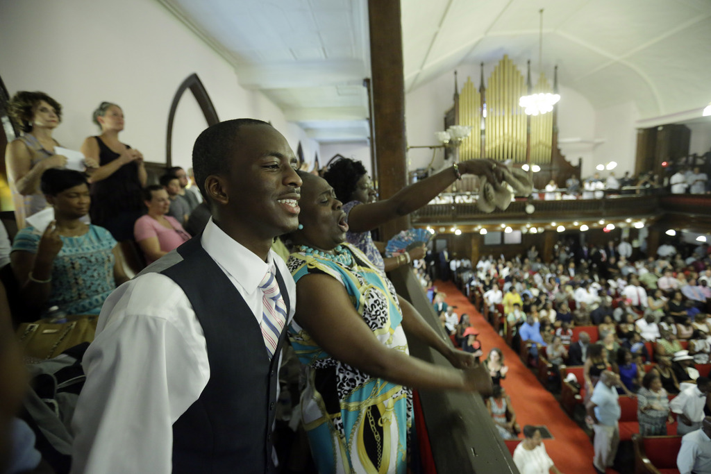 Parishioners Shakur Francis, left, and Karen Watson-Fleming sing at the Emanuel A.M.E. Church Sunday, June 21, 2015, in Charleston, S.C., four days after a mass shooting that claimed the lives of it's pastor and eight others. (AP Photo/David Goldman, Pool)