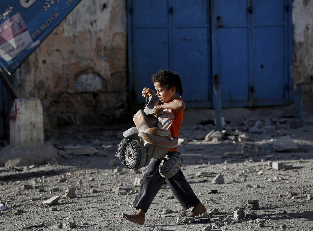 A Palestinian girl walks with a toy that she salvaged from debris of the el-Yazje apartment building which was destroyed following an overnight Israeli missile strike in Gaza City, Thursday, July 17, 2014. The Israeli military says it has struck 37 targets in Gaza ahead of a five-hour humanitarian cease-fire meant to allow civilians to stock up after 10 days of fighting. The Gaza Interior Ministry says four people were killed and that a 75-year-old woman died of wounds from the day before. The Israeli army says Hamas fired 11 rockets at Israel early Thursday. Palestinian health officials say that in total, at least 225 Palestinians have been killed. On the Israeli side, one man was killed since July 8. (AP Photo/Lefteris Pitarakis)