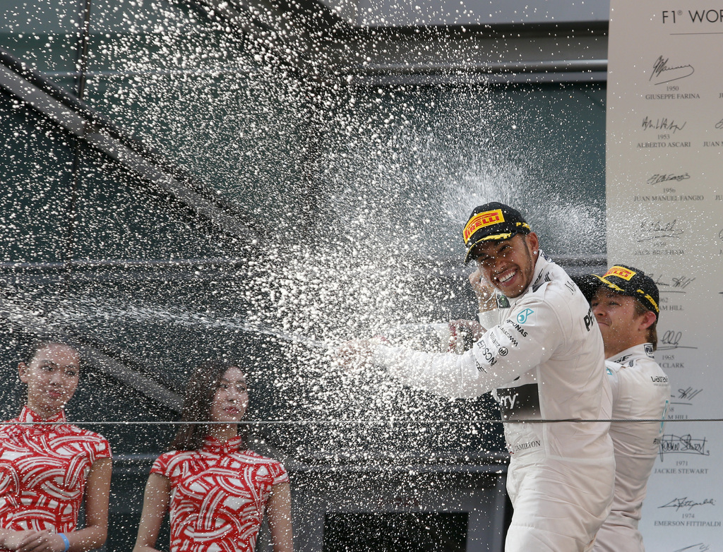 Mercedes driver Lewis Hamilton of Britain is celebrated with champagne by teammate Nico Rosberg, right, of Germany on the podium after winning the Chinese Formula One Grand Prix at Shanghai International Circuit in Shanghai, China, Sunday, April 12, 2015. Rosberg finished second in the race. (AP Photo/Toru Takahashi)
