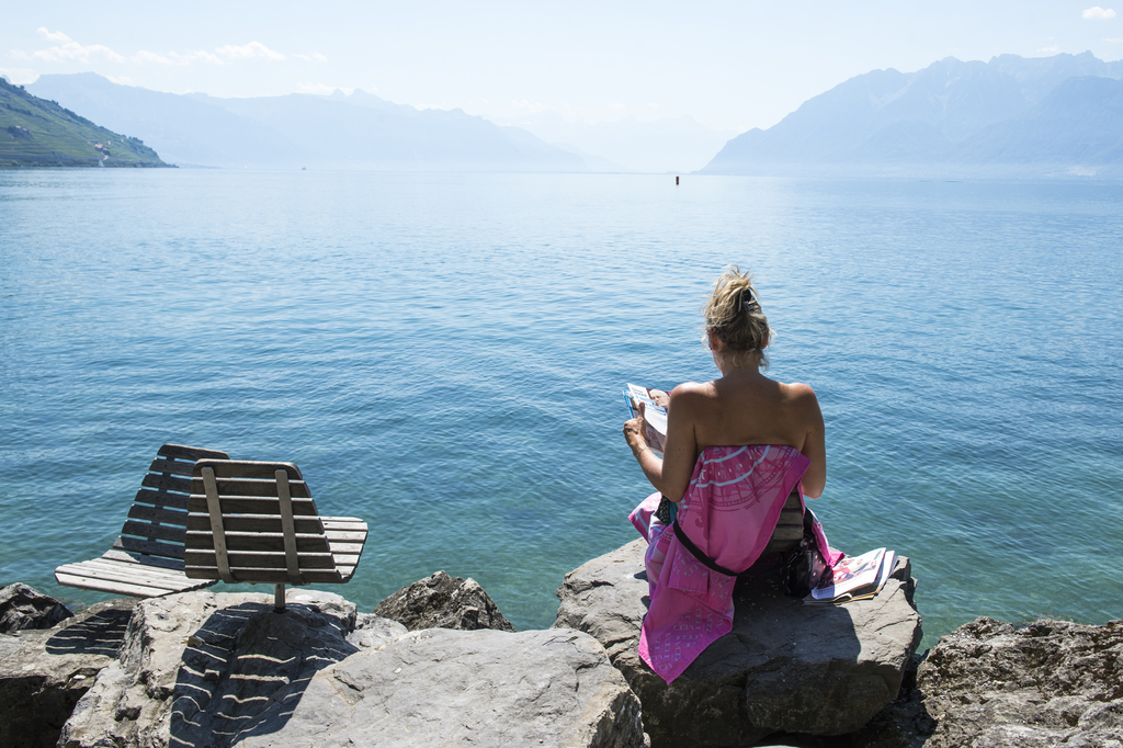 Une dame lit un magazine sur une chaise en bois au bord du lac leman, ce mercredi 1 juillet 2015 a Cully. (KEYSTONE/Dominic Steinmann)....A woman reads a magazine at the board of the Lake Geneva in Saint-Saphorin, Switzerland, Wednesday, July 1, 2015. The European weather forecast is promising high temperatures also for the next few days. (KEYSTONE/Dominic Steinmann)