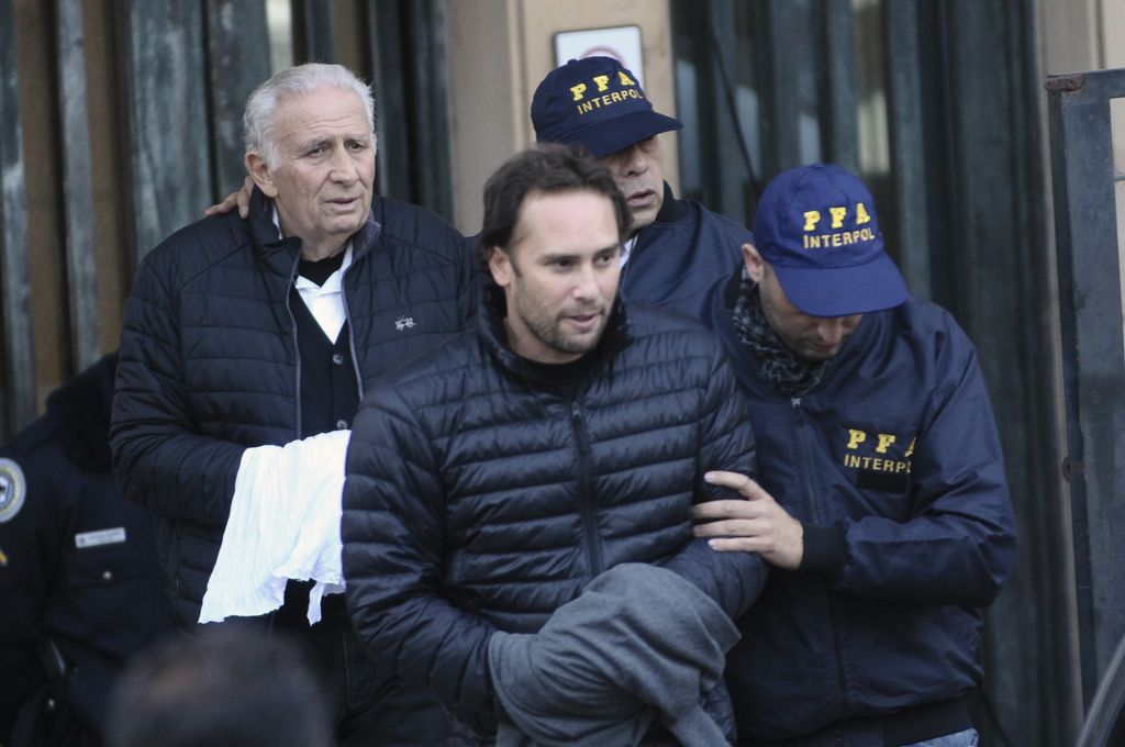 Hugo Jinkis, left, and his son Mariano, center, are escorted by police after they turned themselves in at a federal courthouse in Buenos Aires, Argentina, Thursday, June 18, 2015. The two Argentine businessmen are wanted in the United States in a FIFA bribery case. (AP Photo/Maxi Failla)