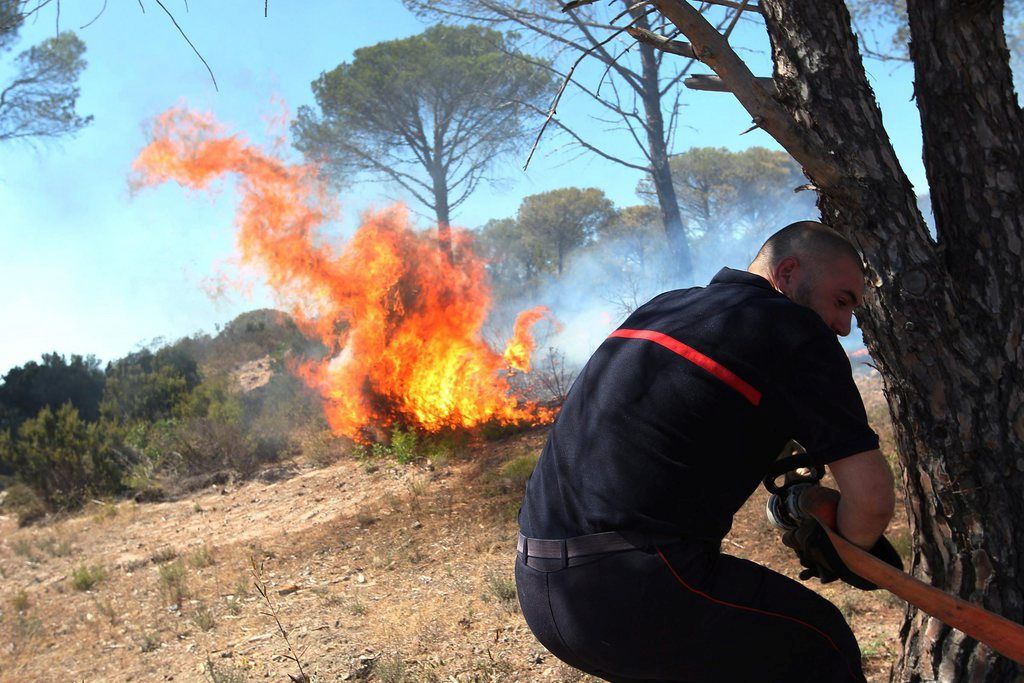 epa04863119 A firefighter tries to extinguish a blaze after a fire broke out at the campsite 'Holiday Green' and in the Domaine du Pin de la Legue, in Frejus, southeastern France, 27 July 2015. Forest fires in southern France have prompted firefighters to evacuate three campsites, affecting 10,000 holidaymakers. Extremely dry conditions and strong winds affecting the south of the country for days helped ignite the fires.  EPA/PHILIPPE ARNASSAN FRANCE OUT; BELGIUM OUT; CORBIS OUT