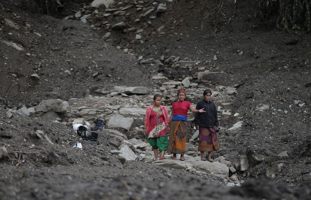 Nepalese women walks through the debris after a landslide in Lumle village, about 200 kilometers (125 miles) west of Kathmandu, Nepal, Thursday, July 30, 2015. Landslides in a mountain area of Nepal buried three villages Thursday, killing several people, authorities said.(AP Photo/Niranjan Shrestha)